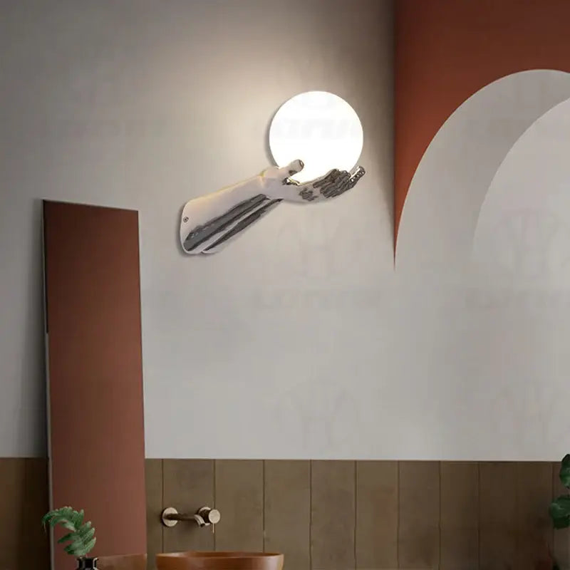 Applique murale avec brand tendu tenant une boule blanche