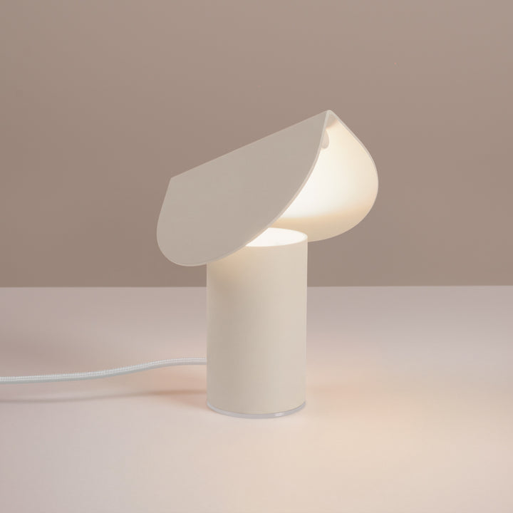 Lampe à poser BISCUIT beige allumée, sur une table