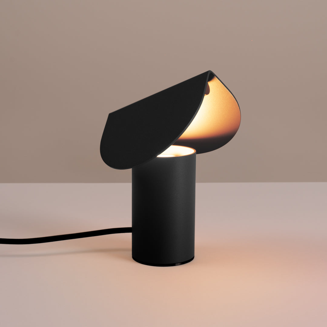 Lampe à poser BISCUIT noir allumée, sur une table
