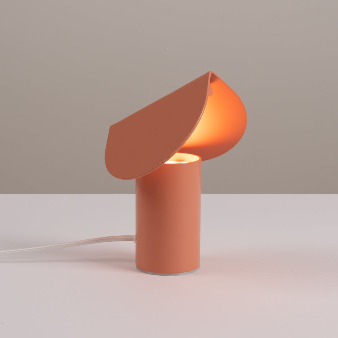 Lampe à poser BISCUIT pêche allumée, sur une table