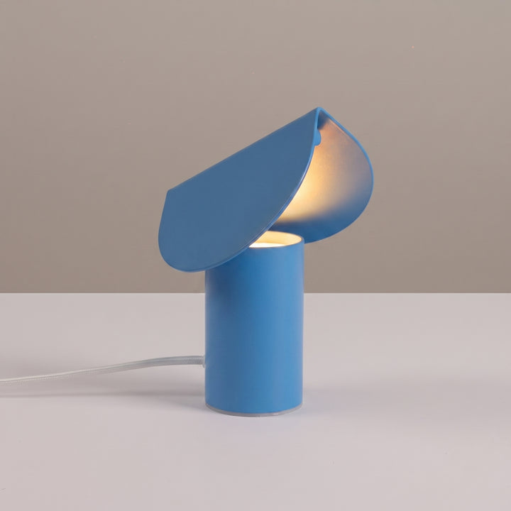 Lampe à poser BISCUIT bleu clair allumée, sur une table