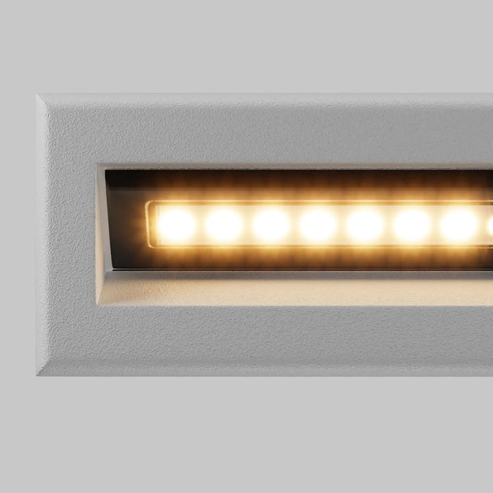 Applique encastrable moderne bosca avec finition texturée blanche et éclairage led chaud long d’une allée