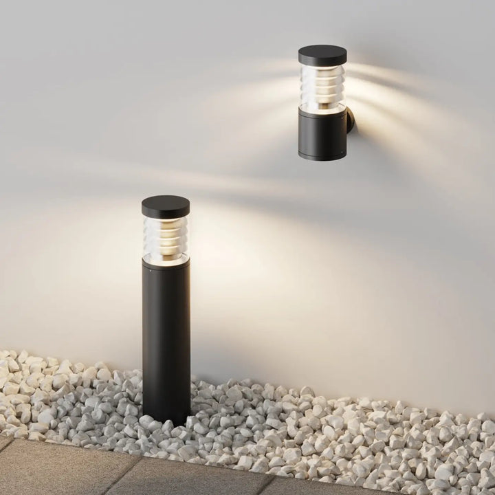 Applique extérieure en acier noir avec verre strié cylindrique et diffuseur givré émettant une lumière chaude