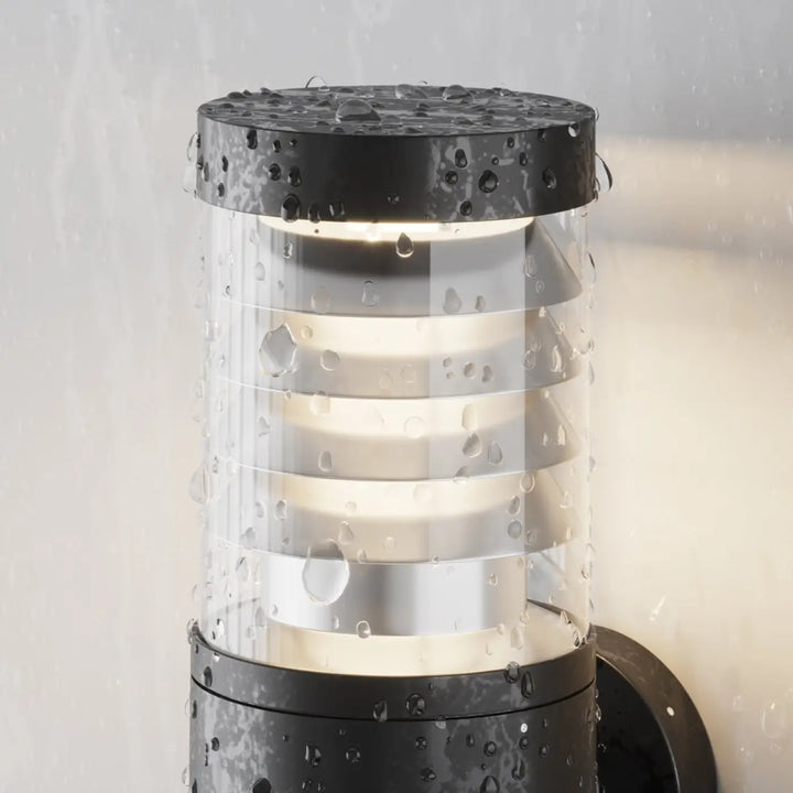 Applique extérieure noire en acier avec verre strié transparent orné danneaux métalliques horizontaux et capuchon texturé