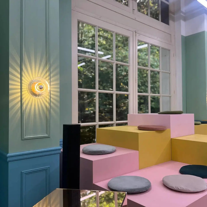 Applique grace murale circulaire en verre soufflé avec centre métallique émettant une lumière chaude et rayonnante