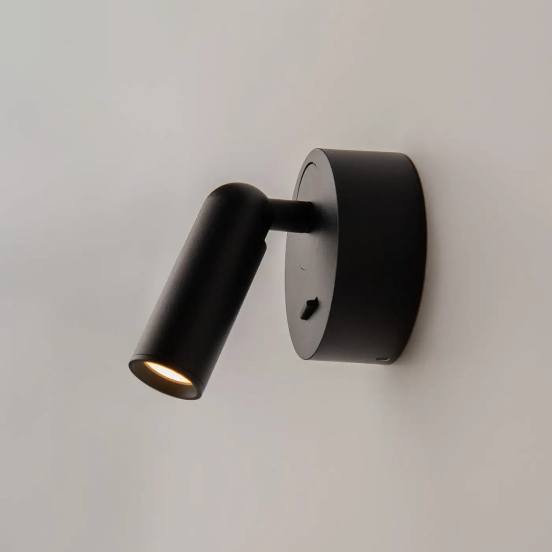 Applique liseuse mirax noire cylindrique avec tête ajustable et module rond émettant une lumière chaude