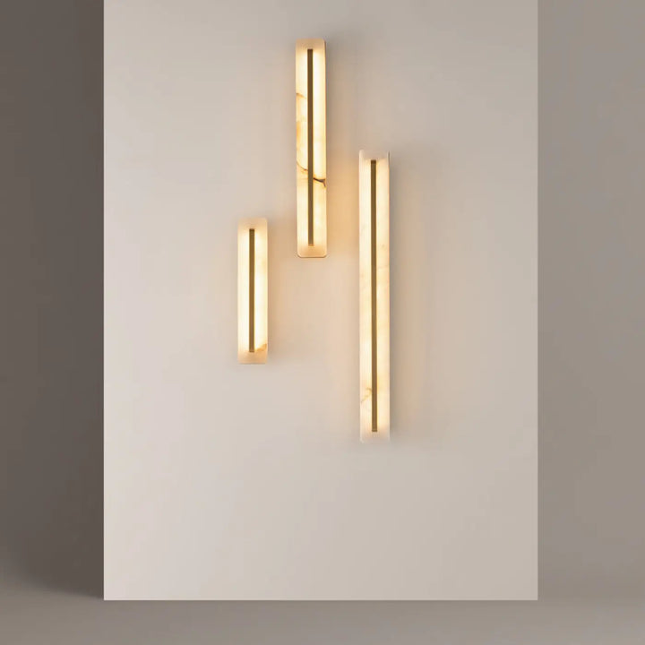 Applique murale albatre avec trois longueurs, finition marbre poli et lumière dorée chaude pour ambiance élégante