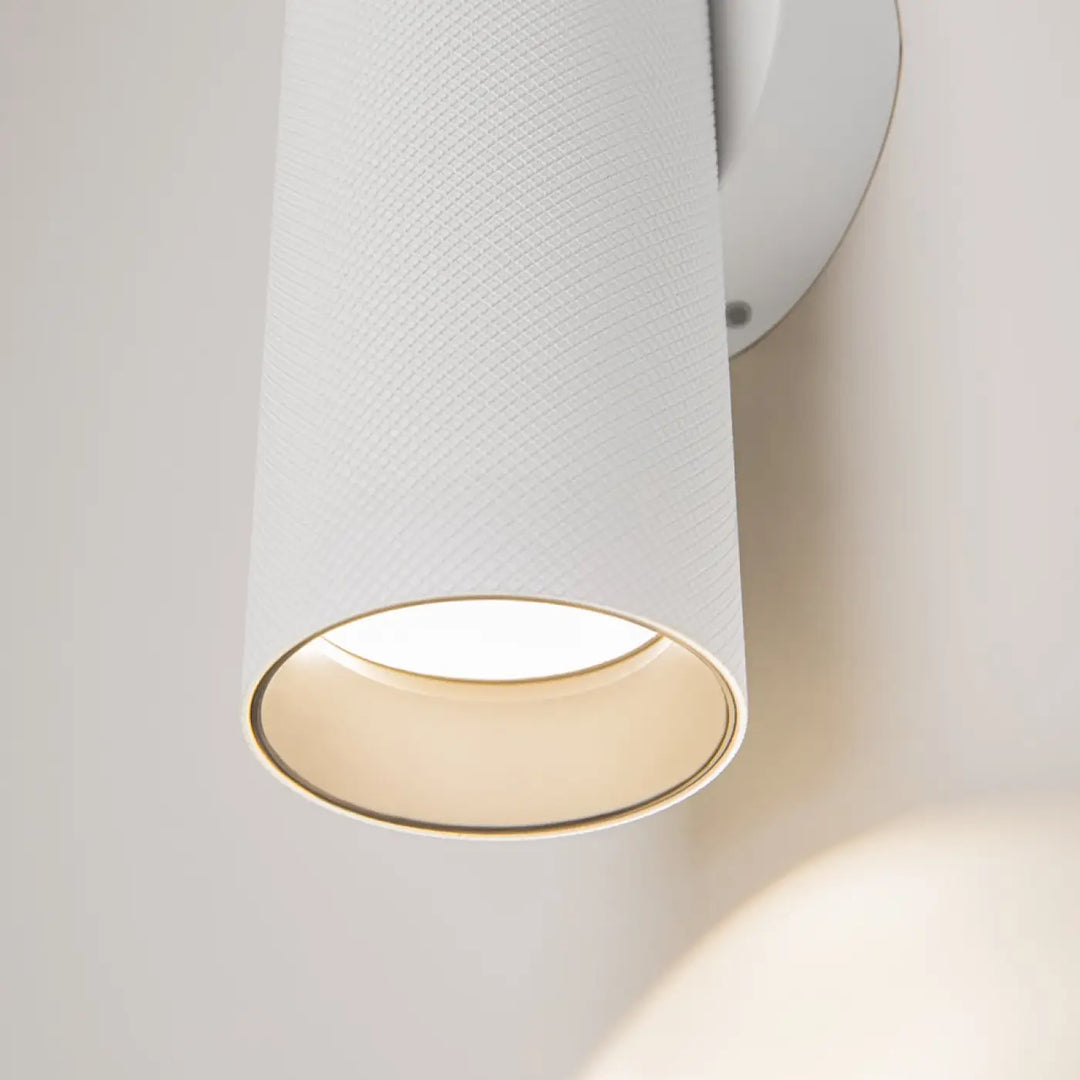 Applique murale artisan cylindrique blanche avec finition en tissu texturé et intérieur ton chaud pour éclairage d’accent