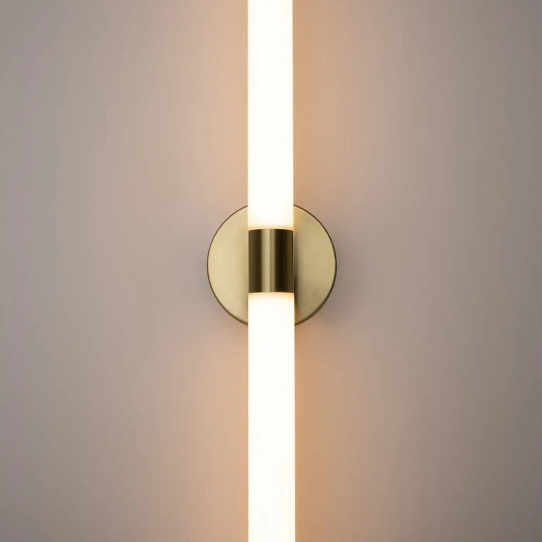 Applique murale axis en acrylique blanc mat avec tube led vertical au fini laiton moderne diffusant une lumière blanc chaud