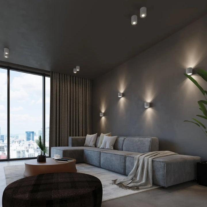 Sectionnel gris avec coussins moelleux et plaid texturé sur laccoudoir accompagné de kinkiet orbis beton