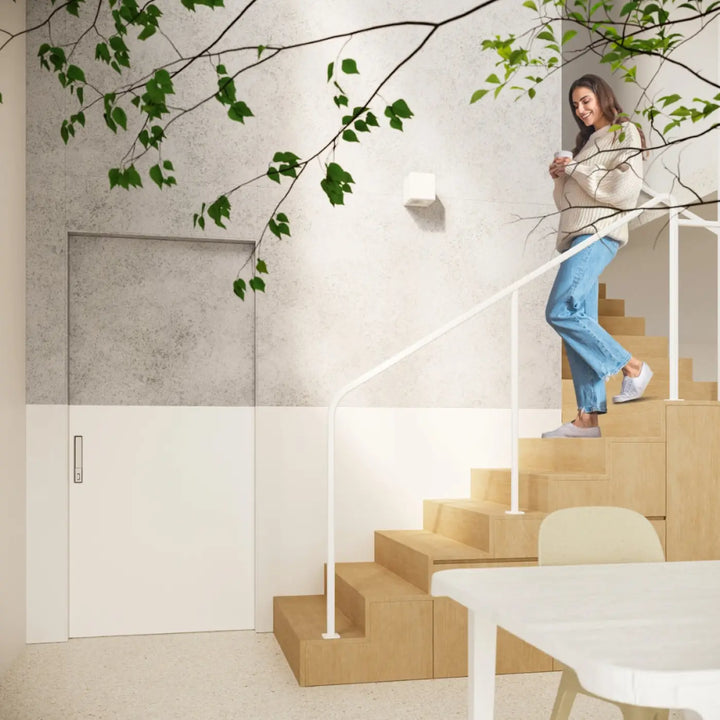 Femme en pull crème et jean bleu sur escaliers en bois avec applique murale céramique nesta belle lumière moderne