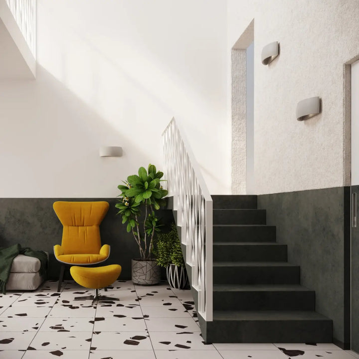 Fauteuil jaune vif avec ottomane assorti accompagné d’une applique murale pontius en céramique gris et enduit structuré