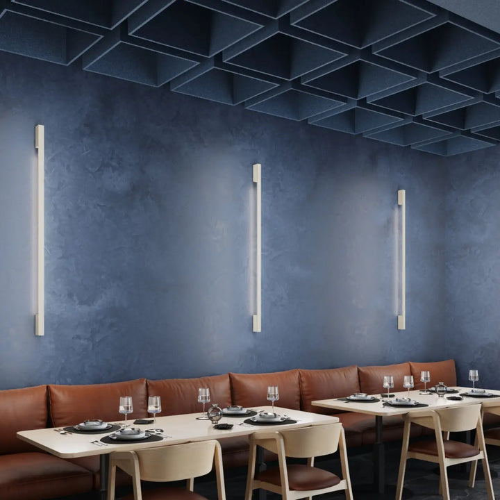 Trois appliques sappo beige sappo 120 led 3000k éclairent un mur bleu profond dans un espace repas moderne