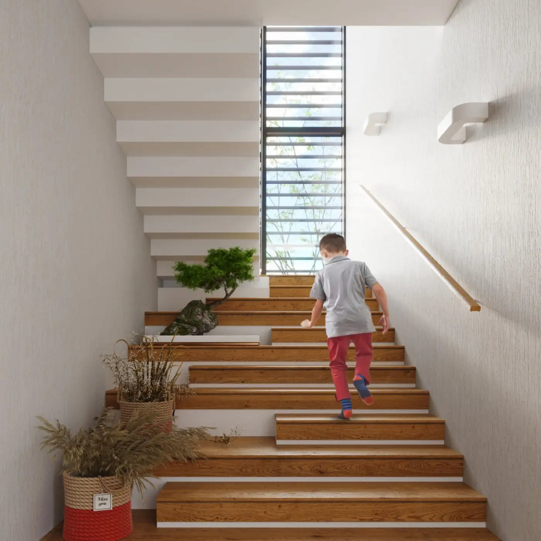 Un enfant en chemise grise et pantalon rouge monte des escaliers en bois avec applique murale moderne en céramique magnet et belle lumière