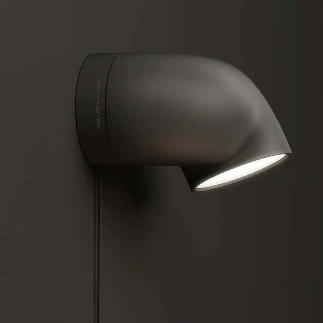 Matte black l’applique ciro murale with a sleek curved design and bright white light featuring base pivote by john august