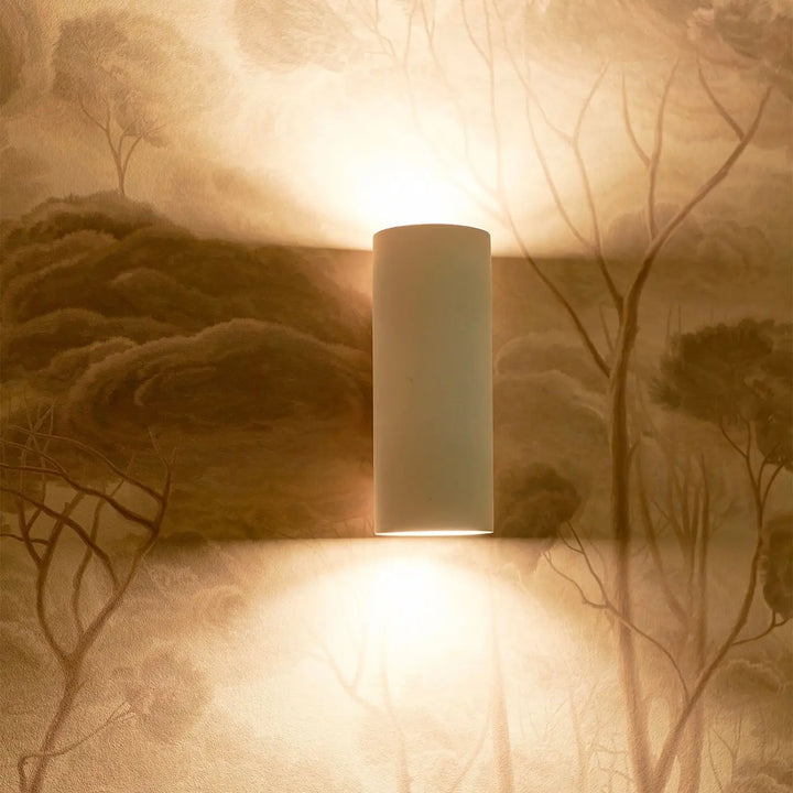 Applique murale parma en plâtre blanc avec design minimaliste éclaire un mur texturé de lumière chaude