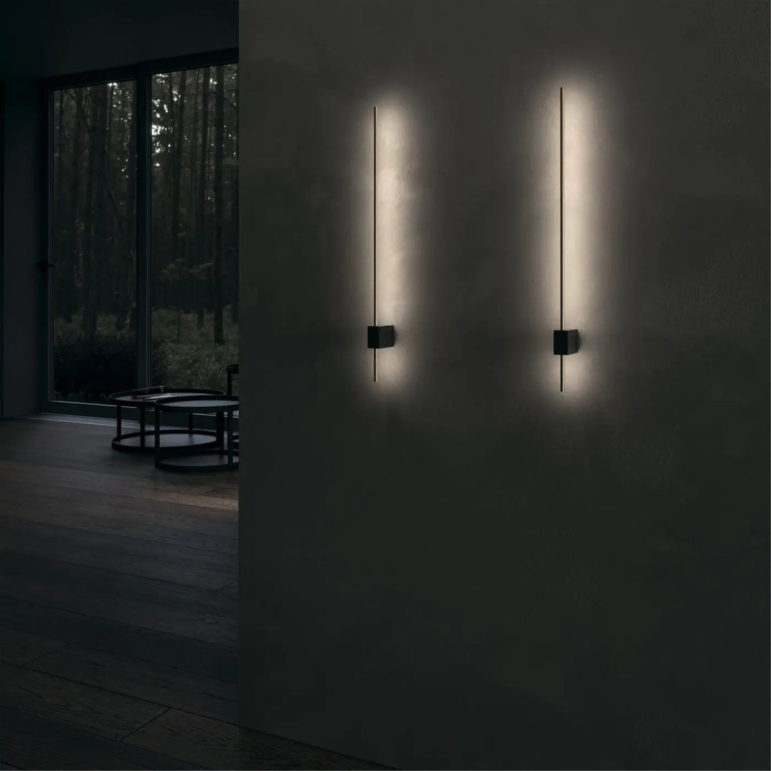 Applique murale pars tige verticale en métal noir avec barres lumineuses verticales émettant une lumière chaude douce