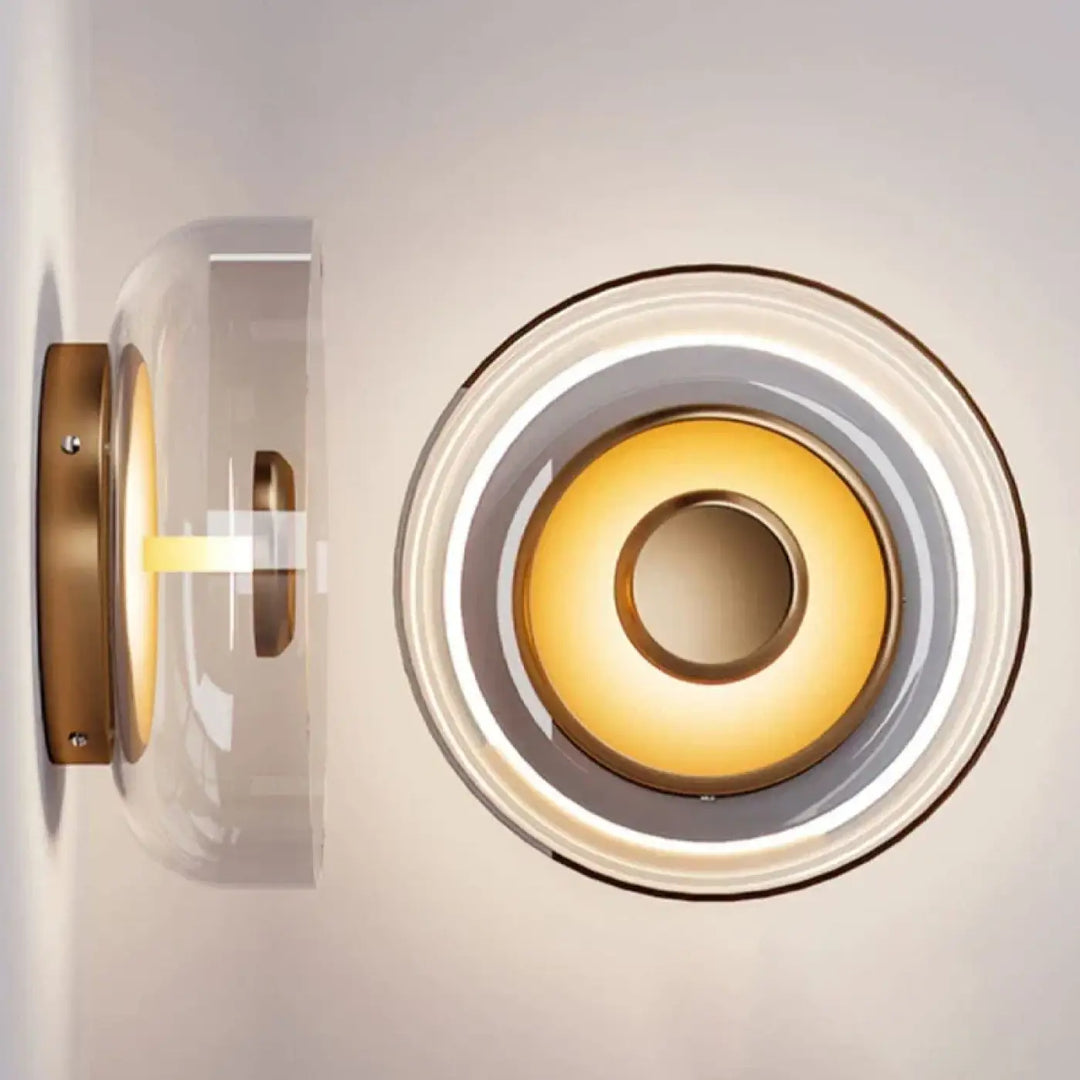 Applique murale oria minimaliste en laiton avec dôme de verre clair et anneaux circulaires rétro émettant une lumière dorée