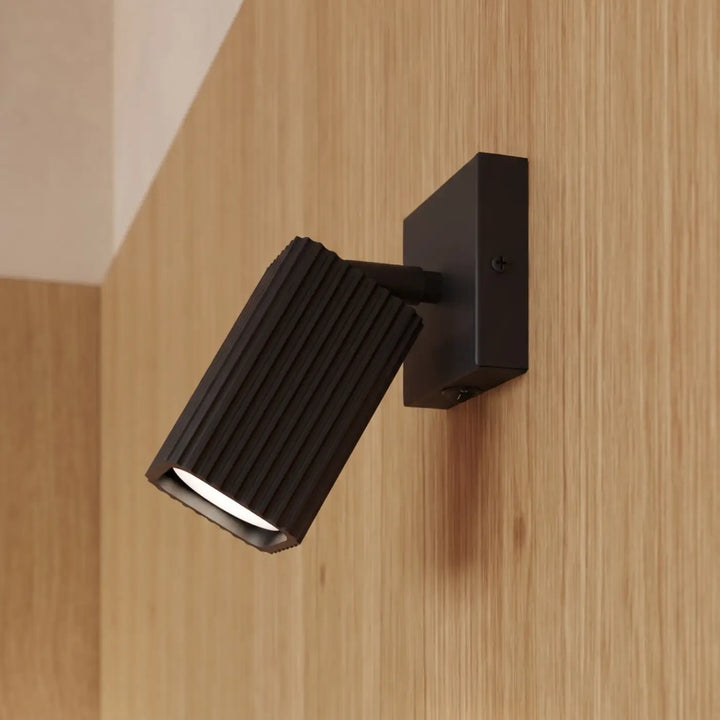 Applique murale Rayo en aluminium noir à réflecteur rainuré, fixée au mur, vue rapprochée
