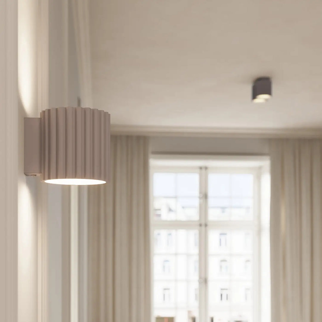 Applique murale aura taupe beige cylindrique avec formes uniques inspirées et lumière chaude diffusée