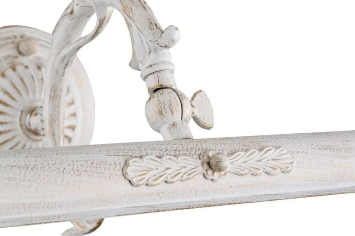 Applique murale picasso en bois blanc vieilli avec bras déporté ornée de feuilles et motifs pour ampoules e14 au-dessus d’un meuble