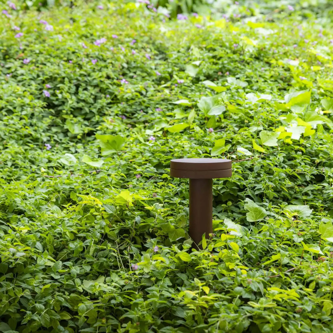 Balise Espot 35 cm brun rouille dans un jardin