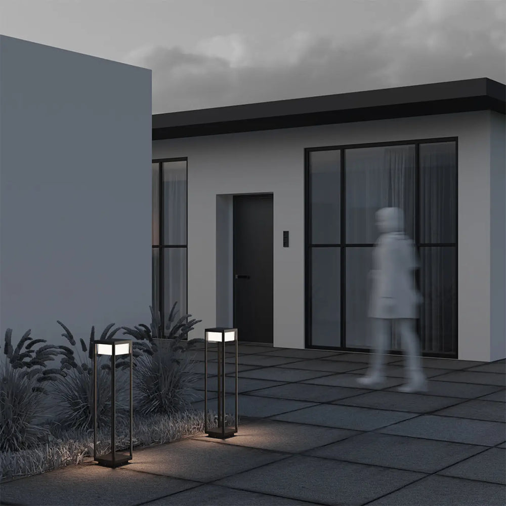 Borne extérieure baker street en aluminium noir avec panneaux en verre carré émettant une lumière chaude
