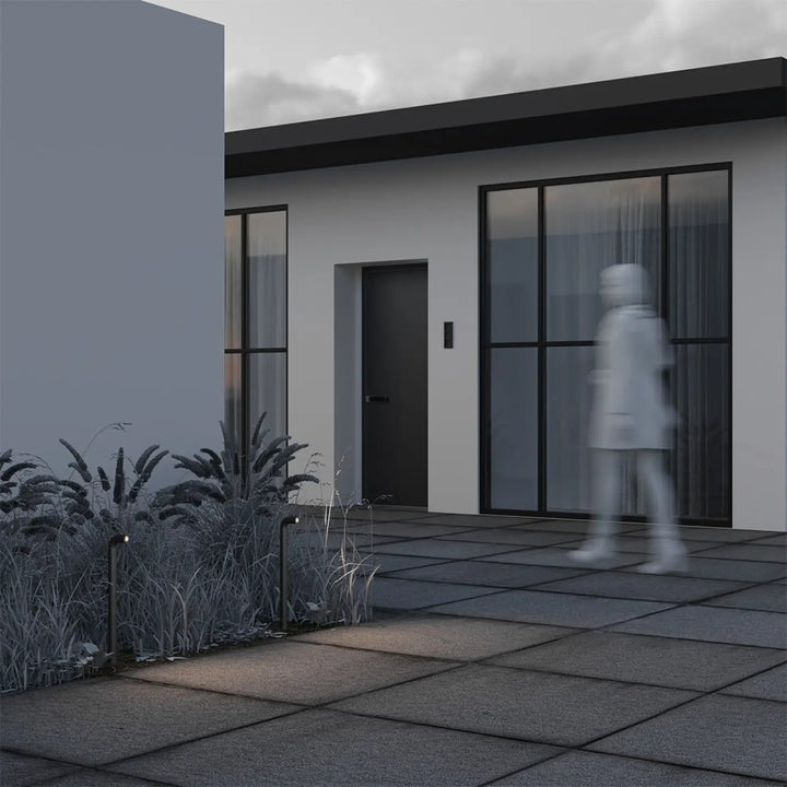 Borne extérieure led sleek cubique en aluminium noir devant maison moderne avec porte grise et fenêtres noires