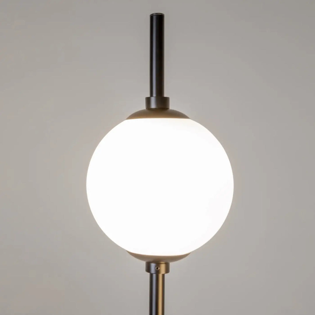 Lampadaire sixth sense avec tige cylindrique noire mate et double globe en verre sphérique blanc éclairé