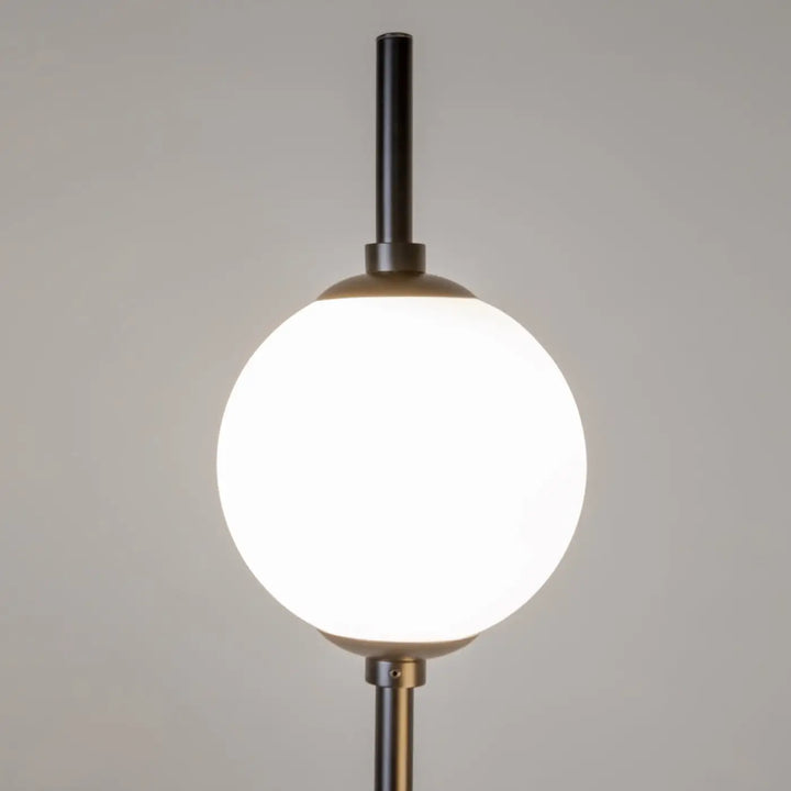 Lampadaire sixth sense avec tige cylindrique noire mate et double globe en verre sphérique blanc éclairé