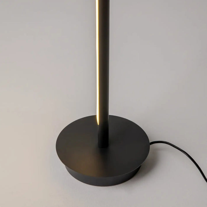 Lampadaire thin noir mat avec led intégrée émettant une lumière chaude, base circulaire pour d’un canapé élégant