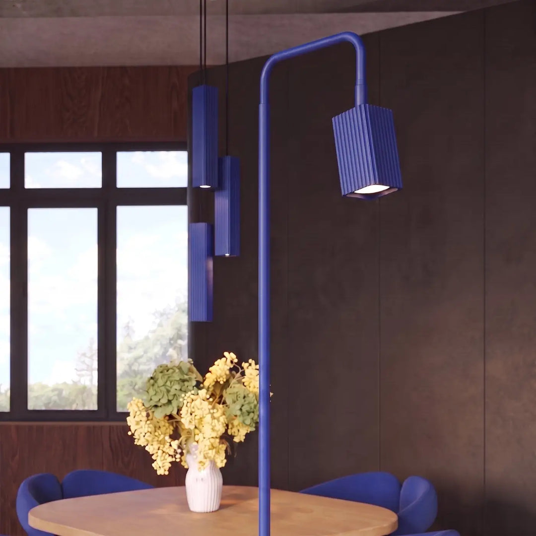 Lampadaire Rayo outremer à spot rainuré près d'une table à manger