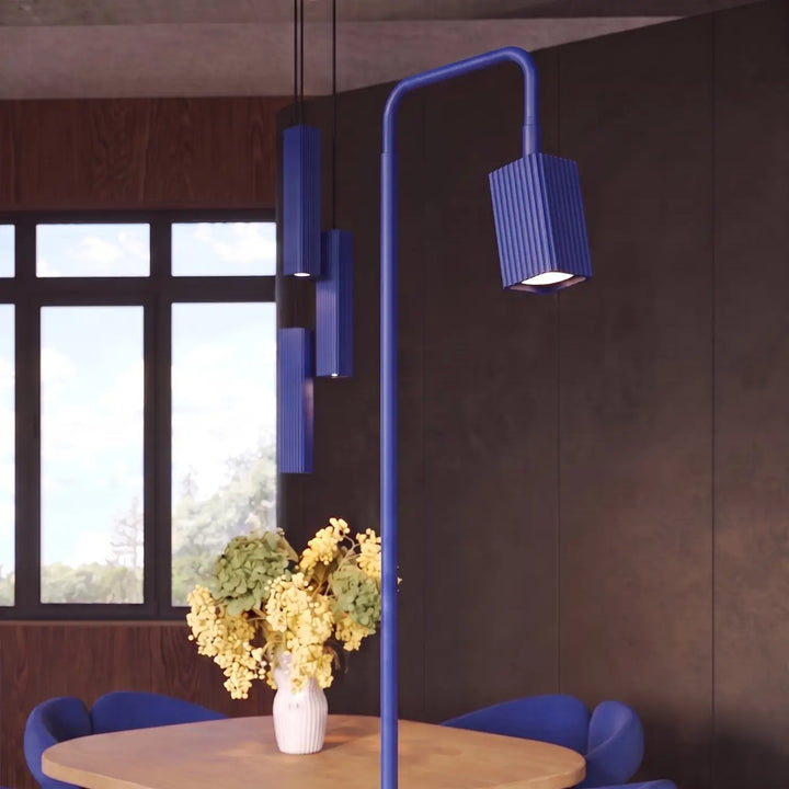 Lampadaire Rayo outremer à spot rainuré près d'une table à manger