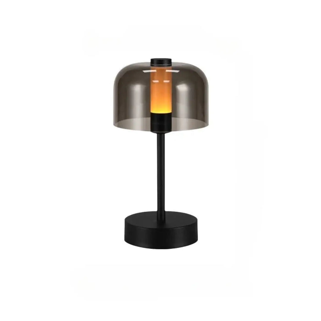 Lampe de table cristo en métal noir avec abat-jour en verre fumé diffusant une lumière orange chaleureuse idéale comme veilleuse