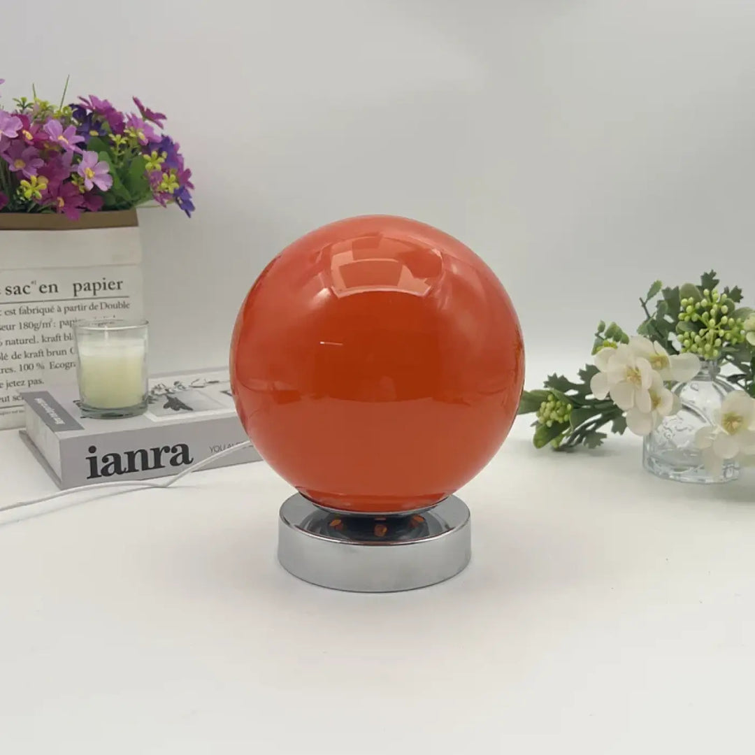 Lampe de chevet lange orange sphérique avec éclairage chaleureux sur socle chrome pour une lumière douce et plus qu’un décor
