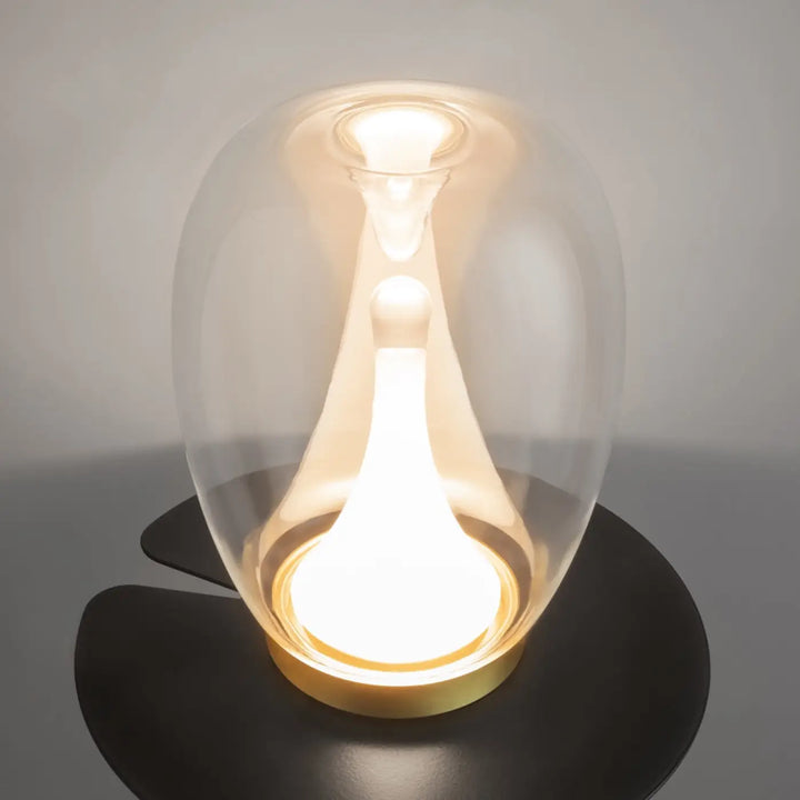 Lampe de chevet led splash avec led intégrée en verre clair en forme de goutte reposant sur base noire élégante