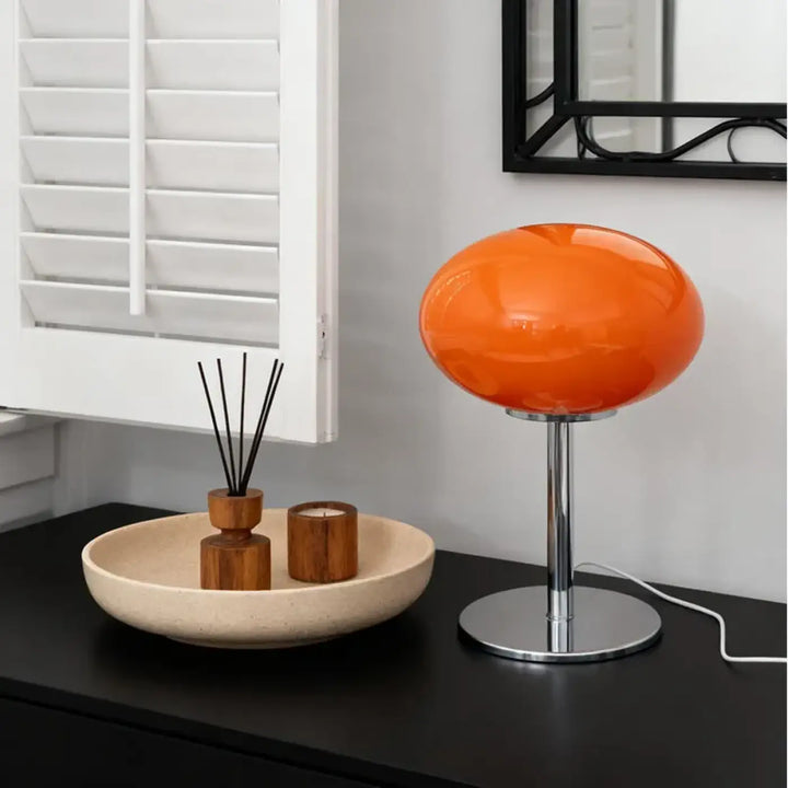 Lampe de chevet minimaliste avec globe en verre orange vibrant et base en chrome où la lumière devient plus qu’un accessoire