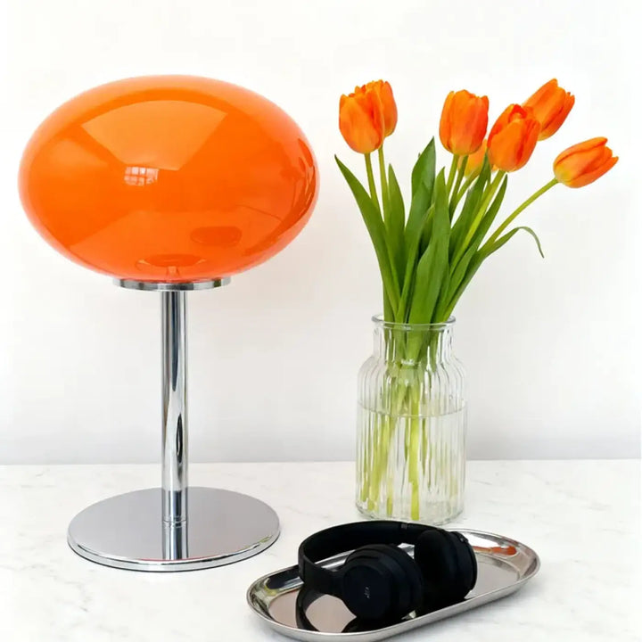 Lampe de chevet minimaliste avec globe orange brillant et pied chrome, lumière devient plus qu’un simple éclairage