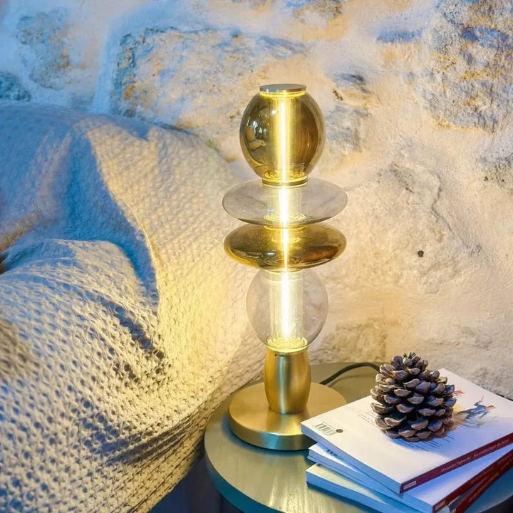 Lampe de chevet léonor avec sphères en verre soufflé ambré translucide sur pied en laiton brossé diffusant une lumière chaude