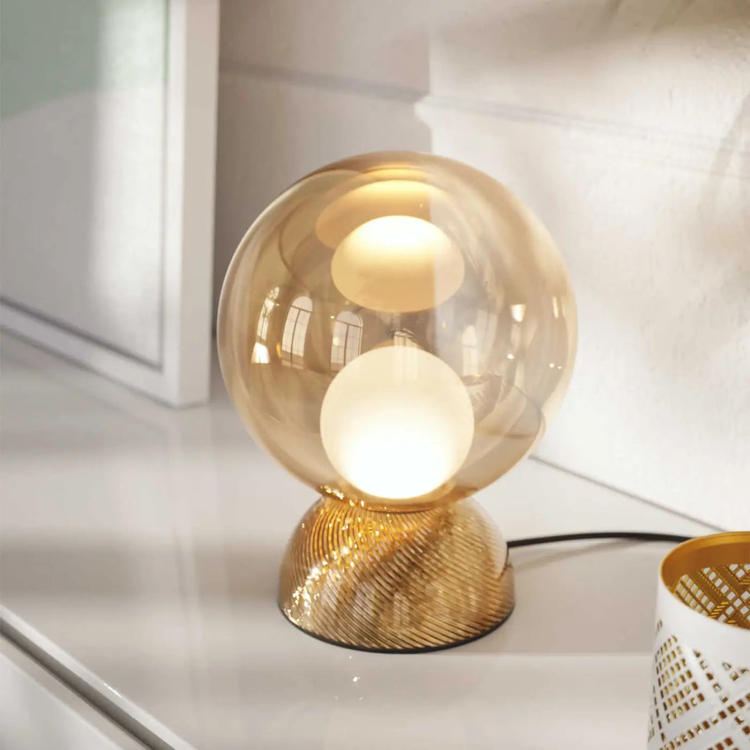 Lampe de chevet charm avec sphère lumineuse cachée en verre chaud et base métallique dorée texturée compacte globe poser charm