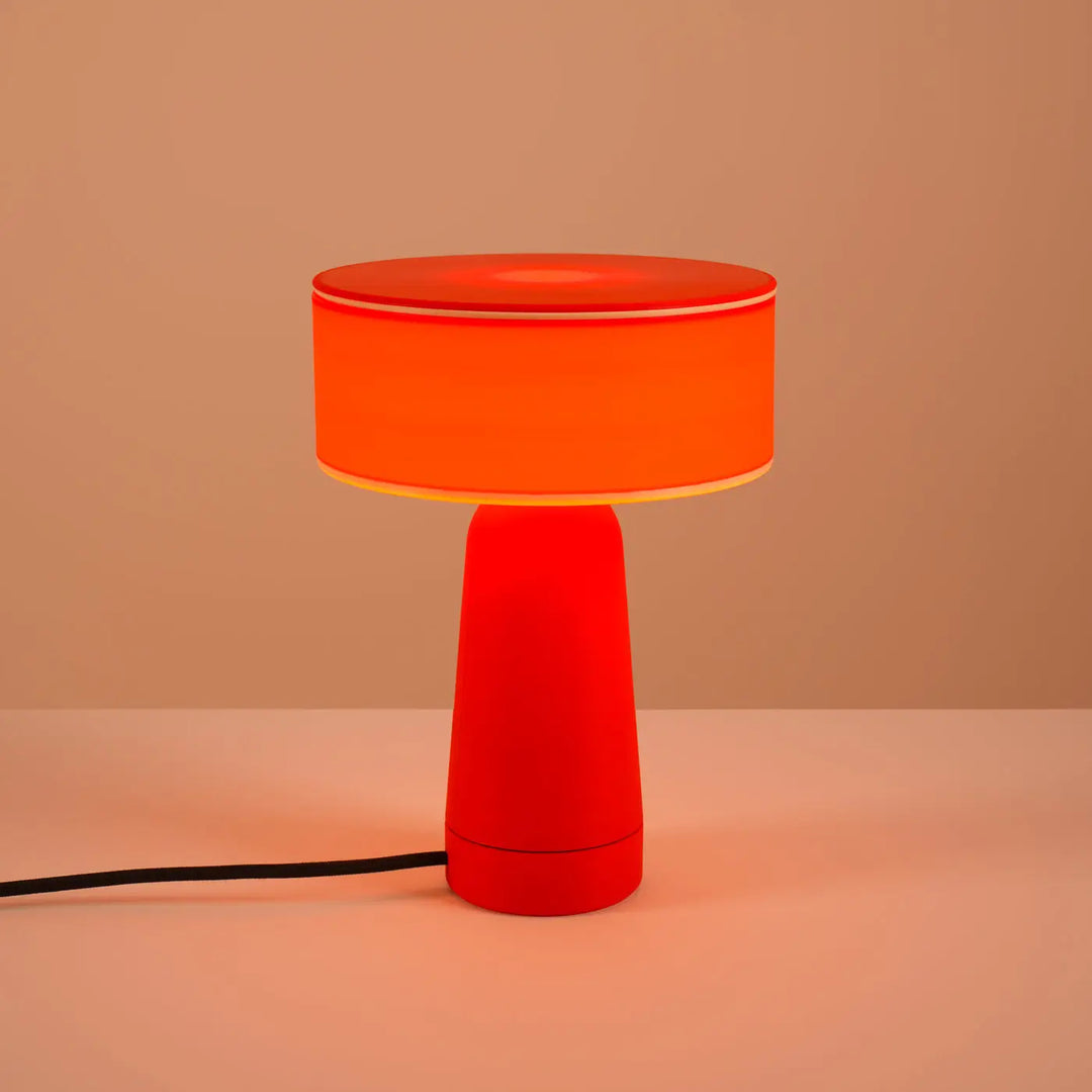 Lampe à poser AXO rouge allumée, sur un meuble