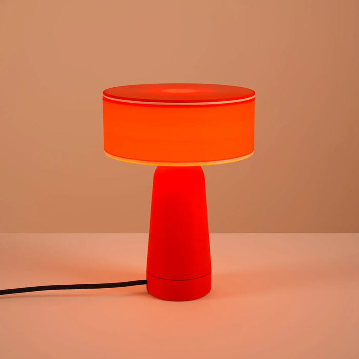 Lampe à poser AXO rouge allumée, sur un meuble