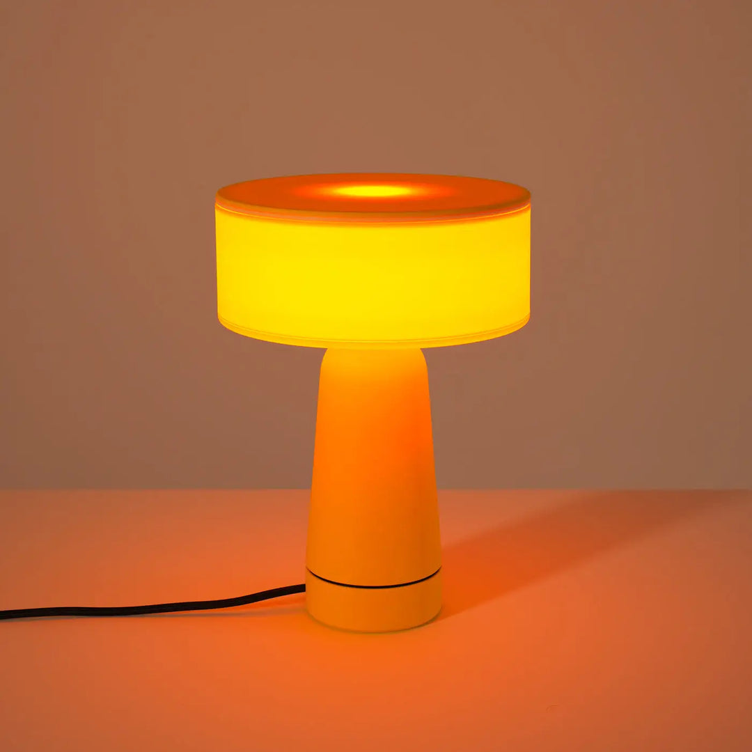 Lampe à poser AXO jaune allumée, sur un meuble
