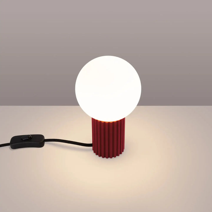 Lampe a poser halo bordeaux avec base cylindrique rouge texturée et ampoule sphérique blanche lumineuse moderne