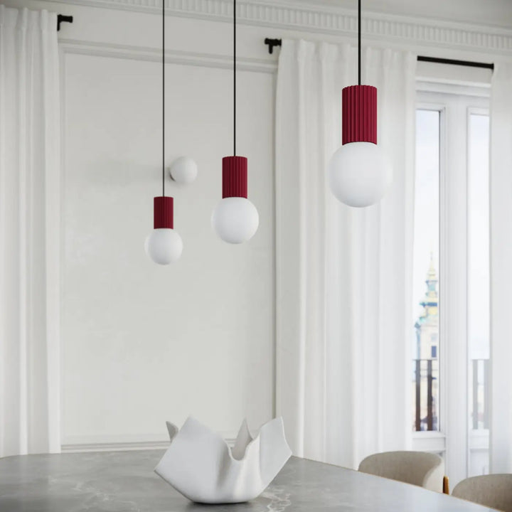 Trois lampes a poser halo bordeaux avec abat-jours globes cylindriques rouges et blancs suspendues par des cordons noirs