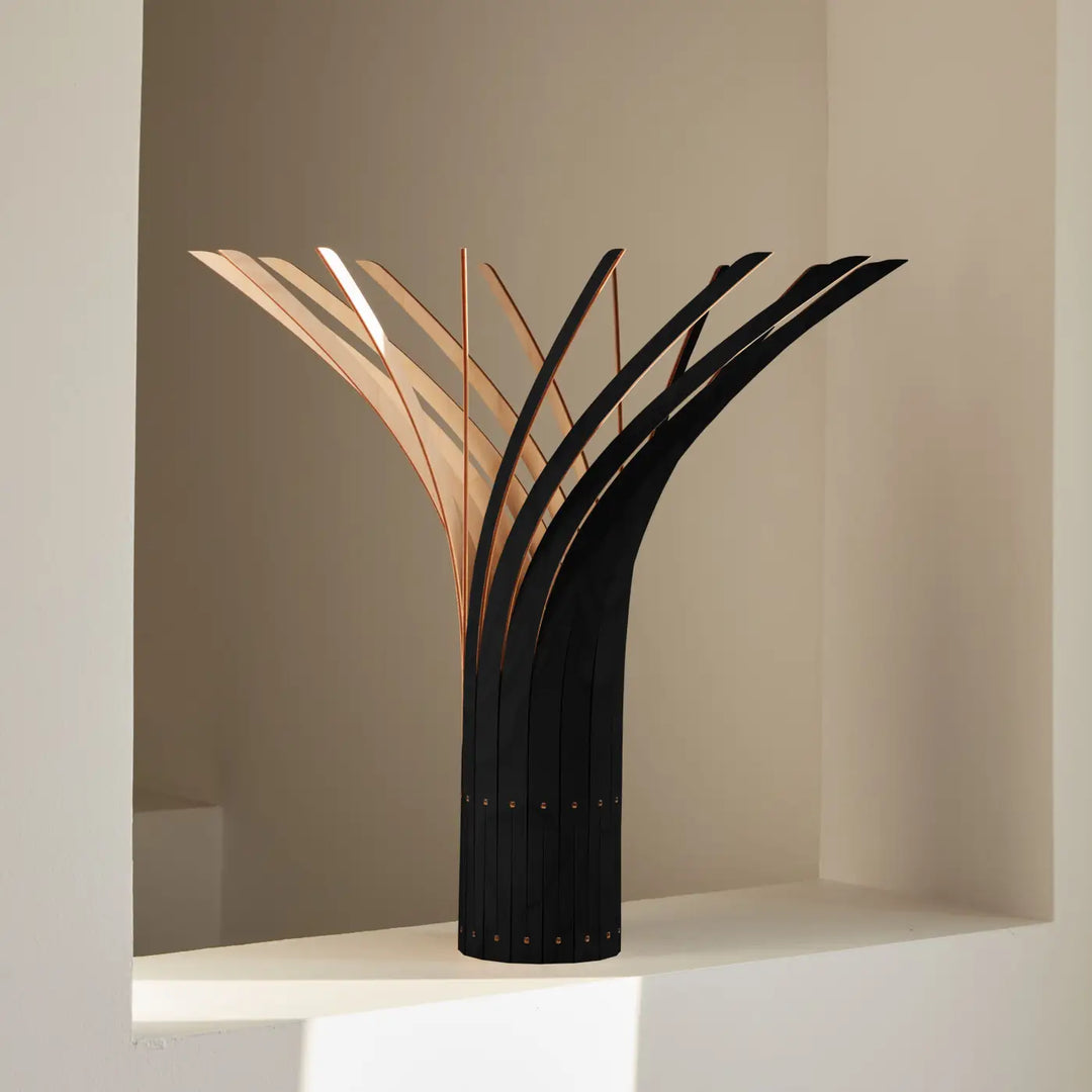Lampe à poser noire et cuivrée avec bras sculpturaux fins et courbés finition naturelle et support stable a Manitj