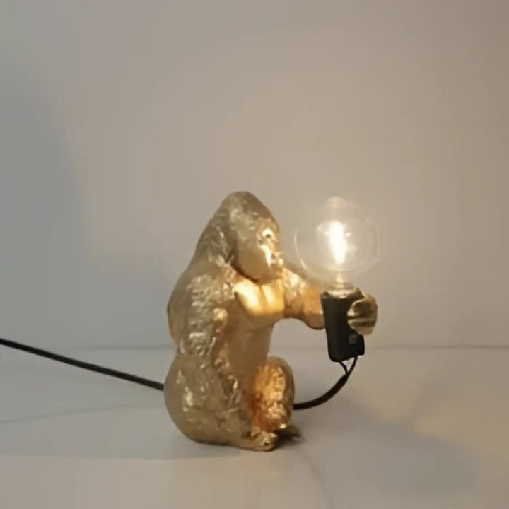 Lampe de table gorenzo artistique gorille dorée tenant une ampoule lumineuse table artistique gorille élégante