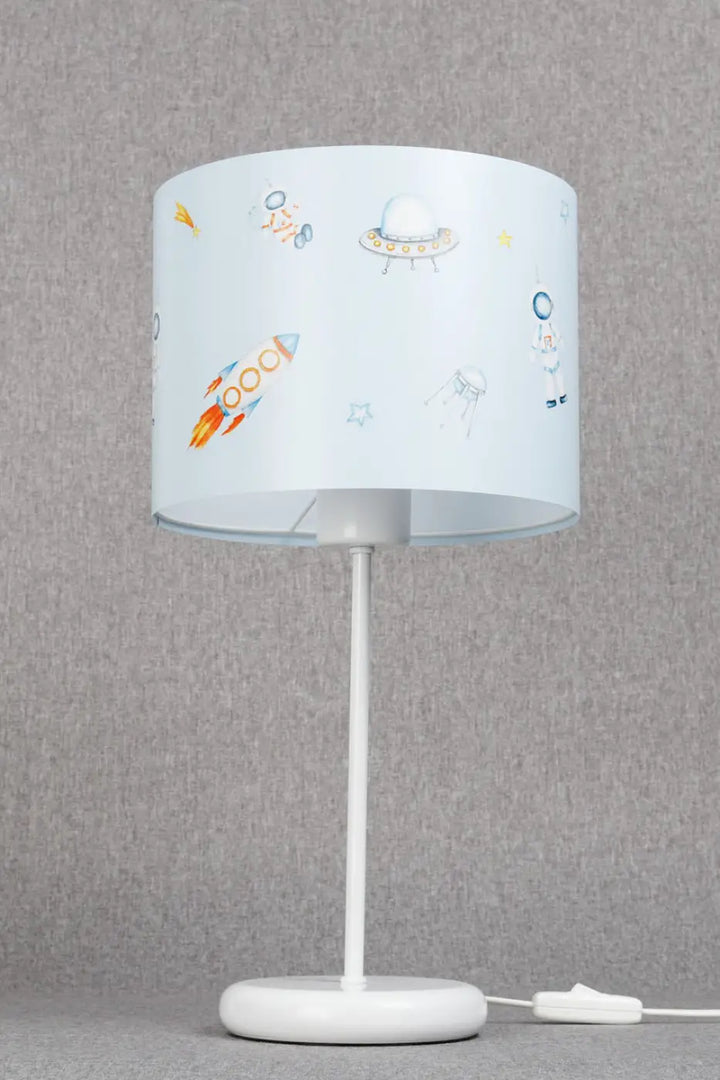 Lampe de table sweet dreams avec abat-jour bleu ciel à motifs espace colorés sur pied blanc pour chambre d’enfant décoration intérieure