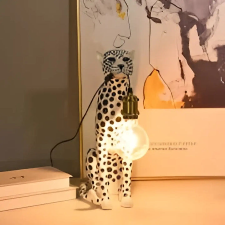 Lampe de table felina en céramique blanche en forme de chat tacheté avec ampoule suspendue visible pour table design léopard