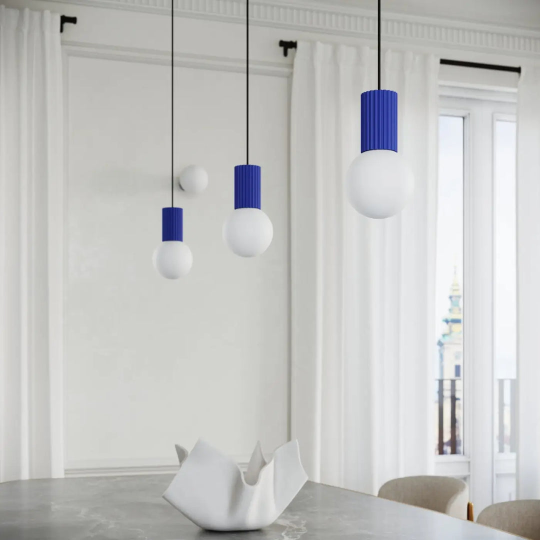 Trois suspensions lampe halo avec abat-jours cylindriques bleus outremer nervurés et ampoules sphériques blanches mat